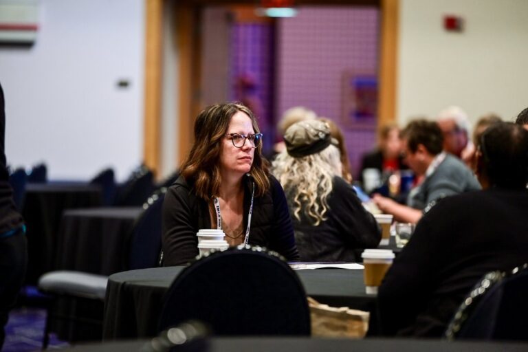 Attendees at tables during a conference session