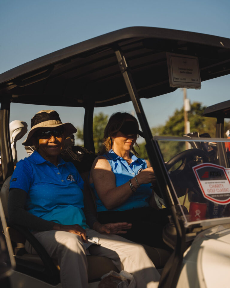 Golfers in a cart with sponsor signage at the ATSG Charity Golf Classic 2025