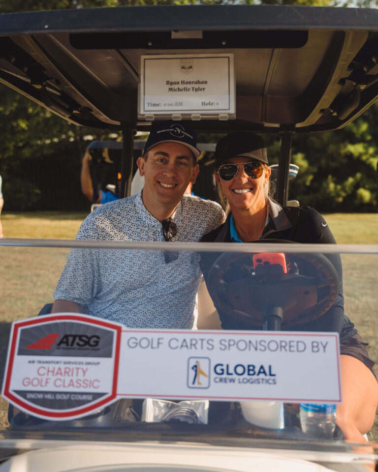 Golfers in a cart with the golf cart sponsor sign at the ATSG Charity Golf Classic 2025