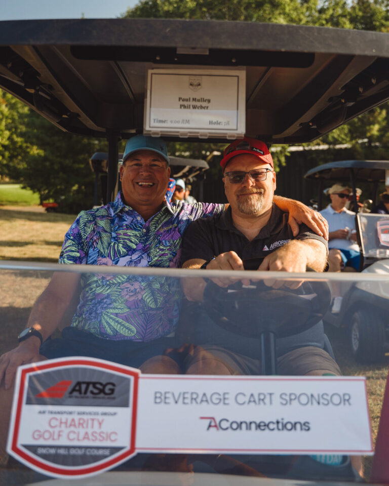 Golfers in a cart with the beverage cart sponsor sign at the ATSG Charity Golf Classic 2025