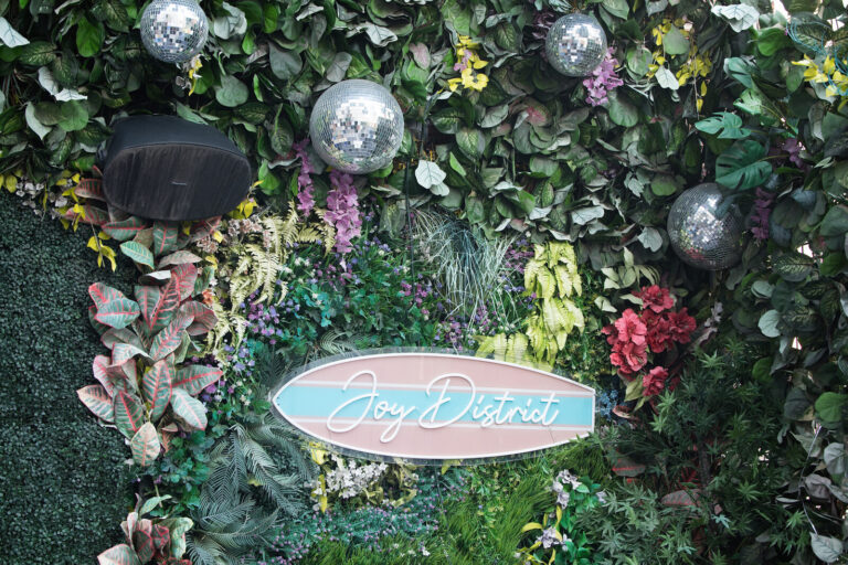 Joy District sign on the greenery wall at the AWE Symposium reception at Joy District, Chicago