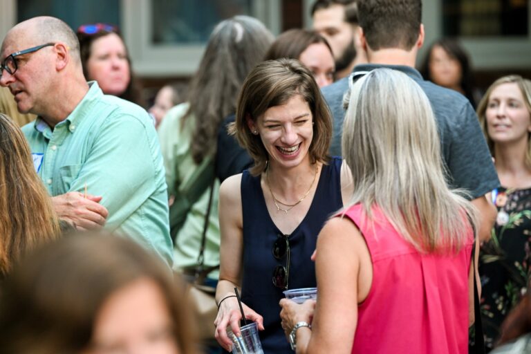 Attendee laughing with colleagues at the AWE symposium reception at Joy District, Chicago
