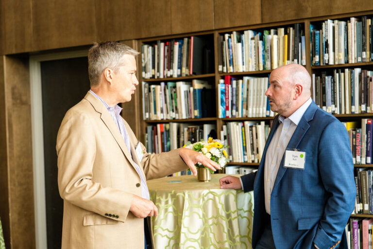 Two guests talking beside a cocktail table in the museum library