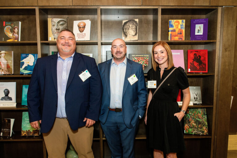 Guests posing in front of the museum library shelves