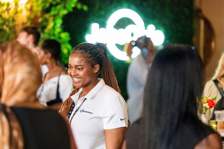 Attendee smiling near the JobsOhio neon sign at Black Tech Week