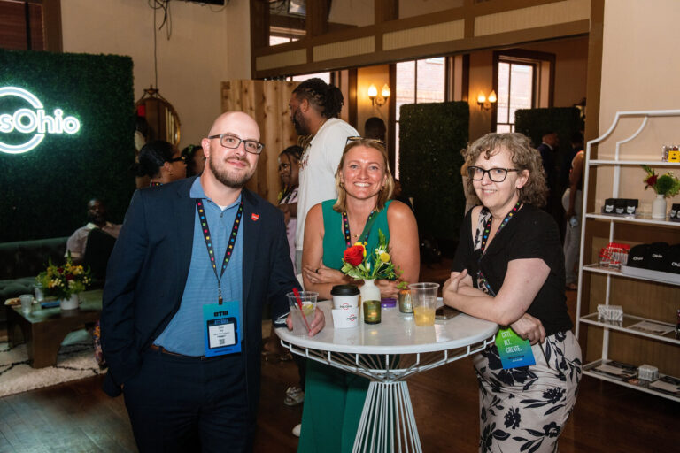 Attendees at a cocktail table near the JobsOhio sign