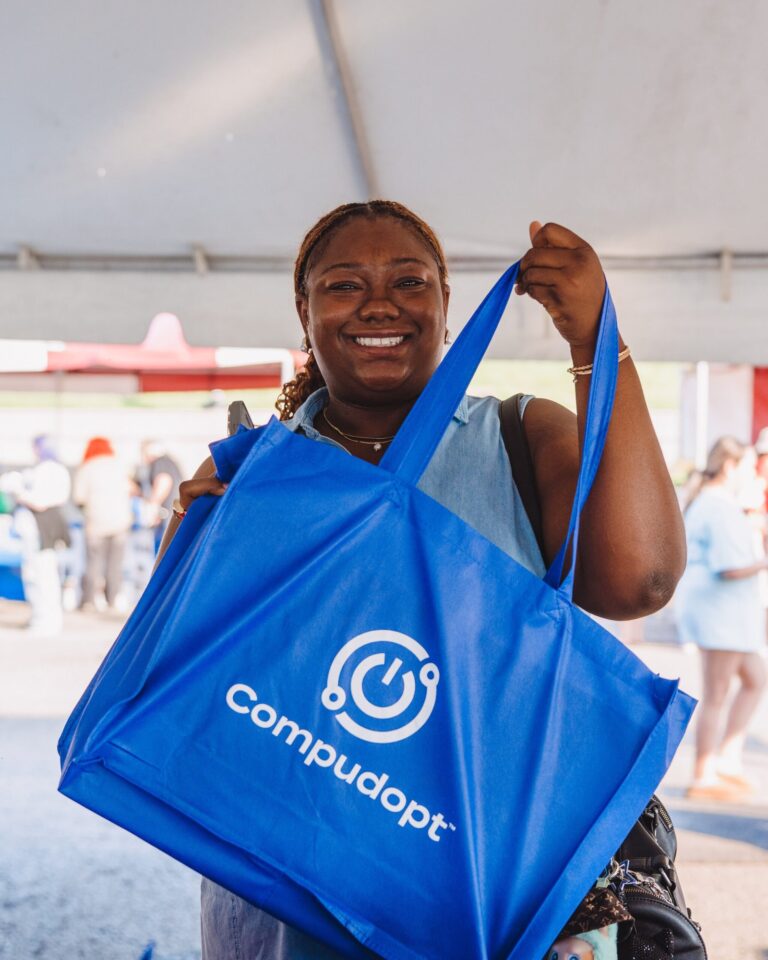 Smiling guest holding a branded tote bag at a corporate community event – Creative Soul Studios