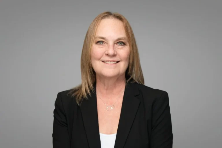 Woman in a black blazer, corporate headshot on gray – Creative Soul Studios