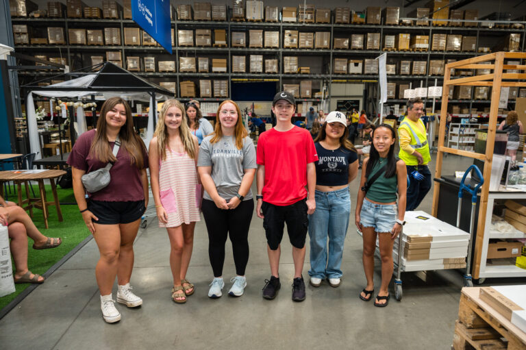 Group of graduates posing in the warehouse aisle at the IKEA Grad Bash Cincinnati 2023