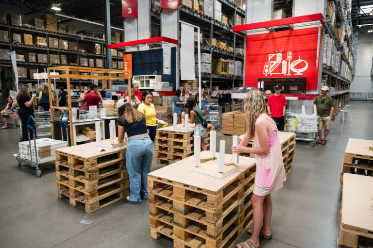 Graduates exploring activity stations among the pallets at the IKEA Grad Bash Cincinnati 2023