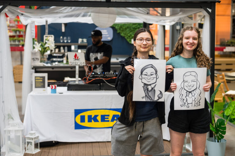 Graduates holding their caricatures at the IKEA booth at the IKEA Grad Bash Cincinnati 2023
