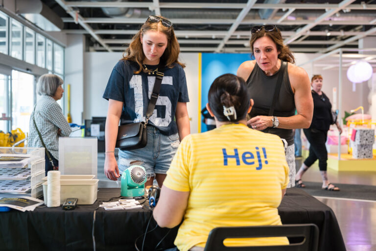 IKEA coworker in a Hej! shirt helping guests at the IKEA Grad Bash Cincinnati 2023