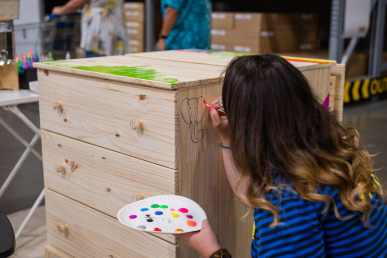 Guest painting a wooden dresser at the IKEA Grad Bash Cincinnati 2023