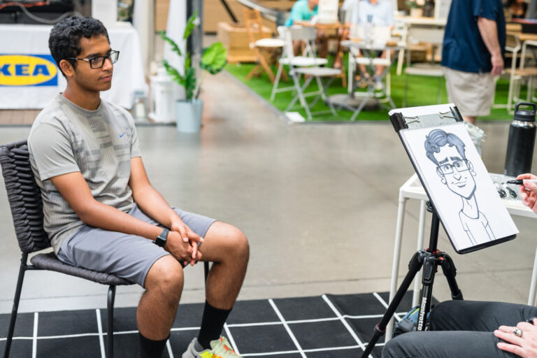 Graduate sitting for a caricature at the IKEA Grad Bash Cincinnati 2023