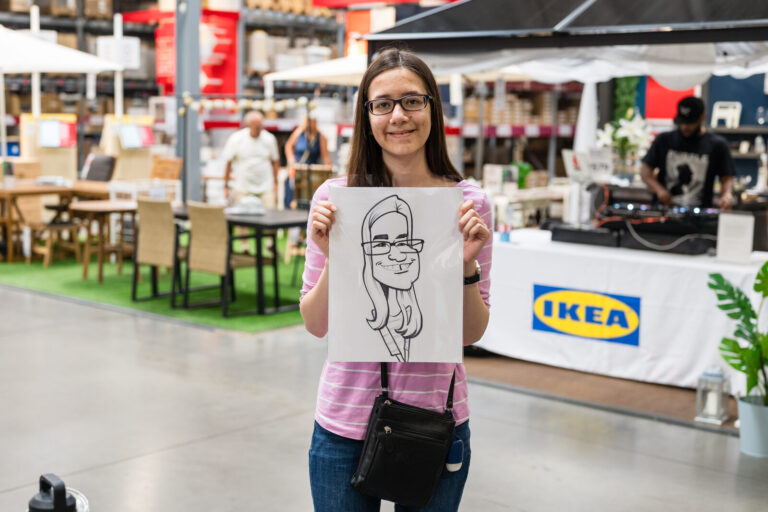 Graduate holding up her caricature at the IKEA Grad Bash Cincinnati 2023