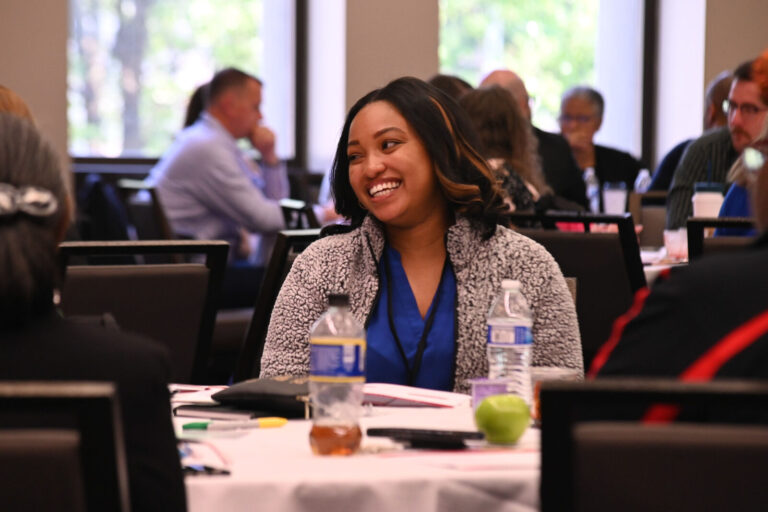 Attendee smiling during a table discussion at LeaderShift