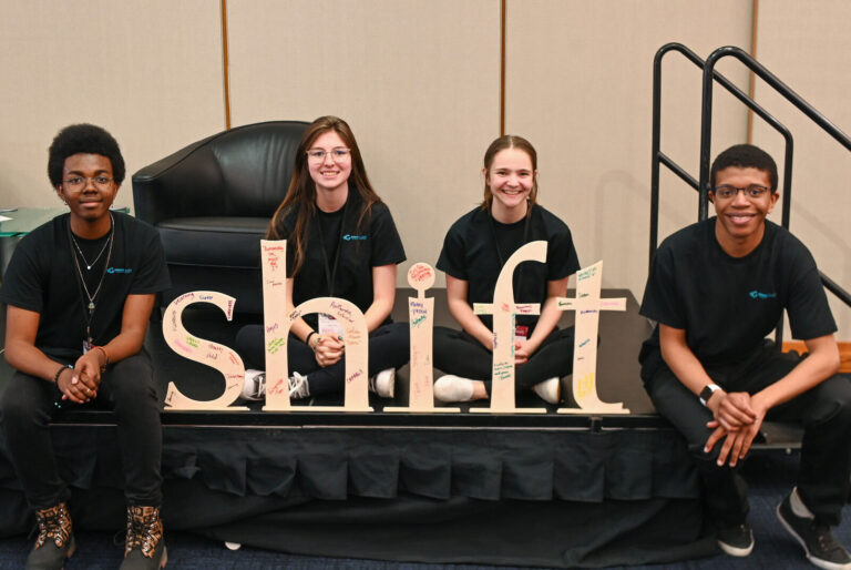 Student volunteers posing with the Shift sign at LeaderShift