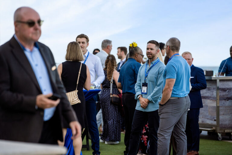 Attendees mingling on the oceanfront lawn at NeoSummit