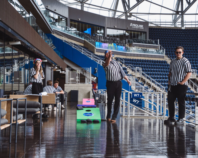 Referees and cornhole in the TQL Stadium concourse at a P&G team event