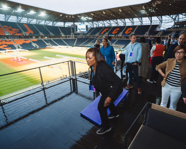 Cornhole with the TQL Stadium field behind at a P&G team event