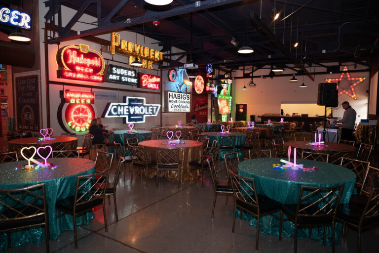 Dinner tables set under vintage neon signs at the P&G Baby Care celebration, American Sign Museum Cincinnati