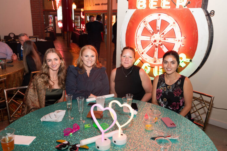 Guests at a table with a neon heart centerpiece at the P&G Baby Care celebration, American Sign Museum Cincinnati