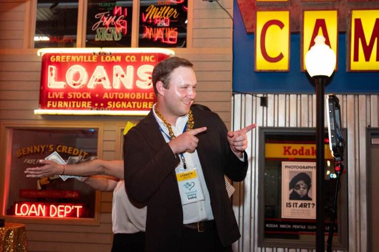 Guest posing by the Loans neon sign at the P&G Baby Care celebration, American Sign Museum Cincinnati