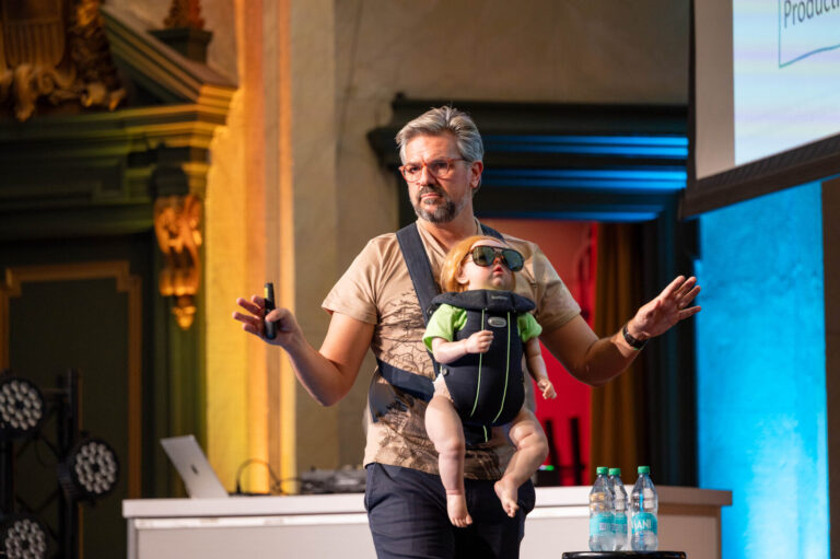 Presenter wearing a baby carrier on stage at the P&G Baby Care event, Music Hall Cincinnati