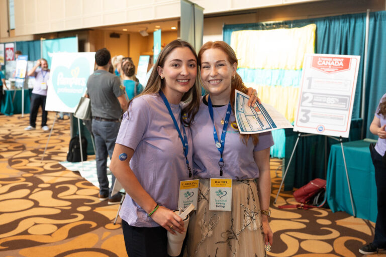 Two attendees posing at a booth at the P&G Baby Care event, Music Hall Cincinnati
