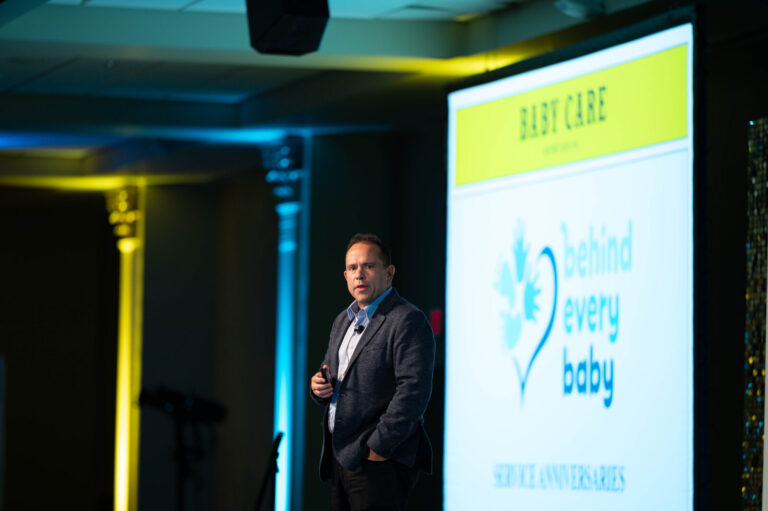 Speaker beside the Behind Every Baby screen at the P&G Baby Care event, Music Hall Cincinnati