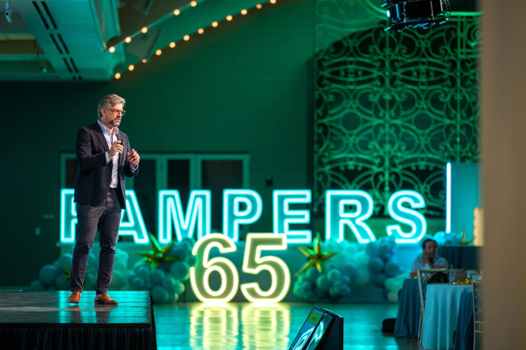 Speaker beside the Pampers 65 neon sign at the P&G Baby Care event, Music Hall Cincinnati