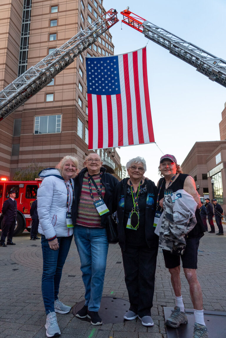 Attendees beneath an American flag raised between fire ladder trucks in Covington