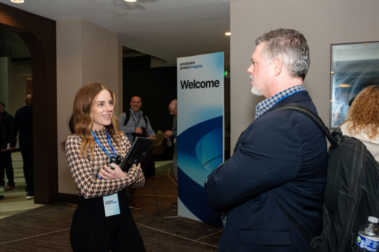 Attendees talking by the welcome sign at Proofpoint Protect Insights