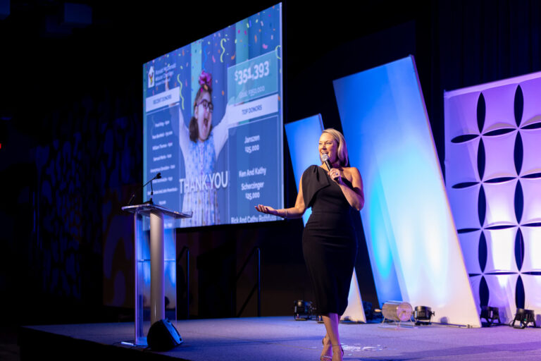 Speaker on stage in front of a thank-you slide at the Ronald McDonald House Charities gala, Northern Kentucky Convention Center