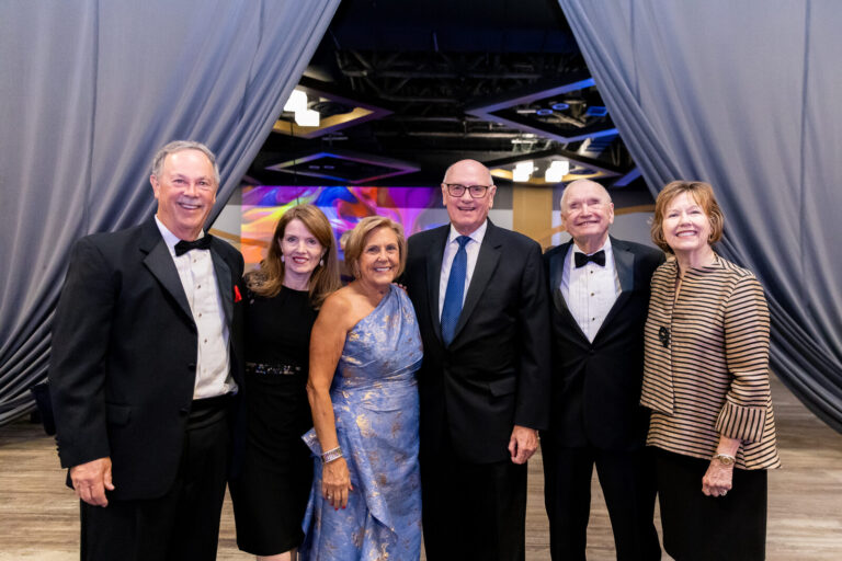 Group photo in front of the stage drapes at the Ronald McDonald House Charities gala, Northern Kentucky Convention Center