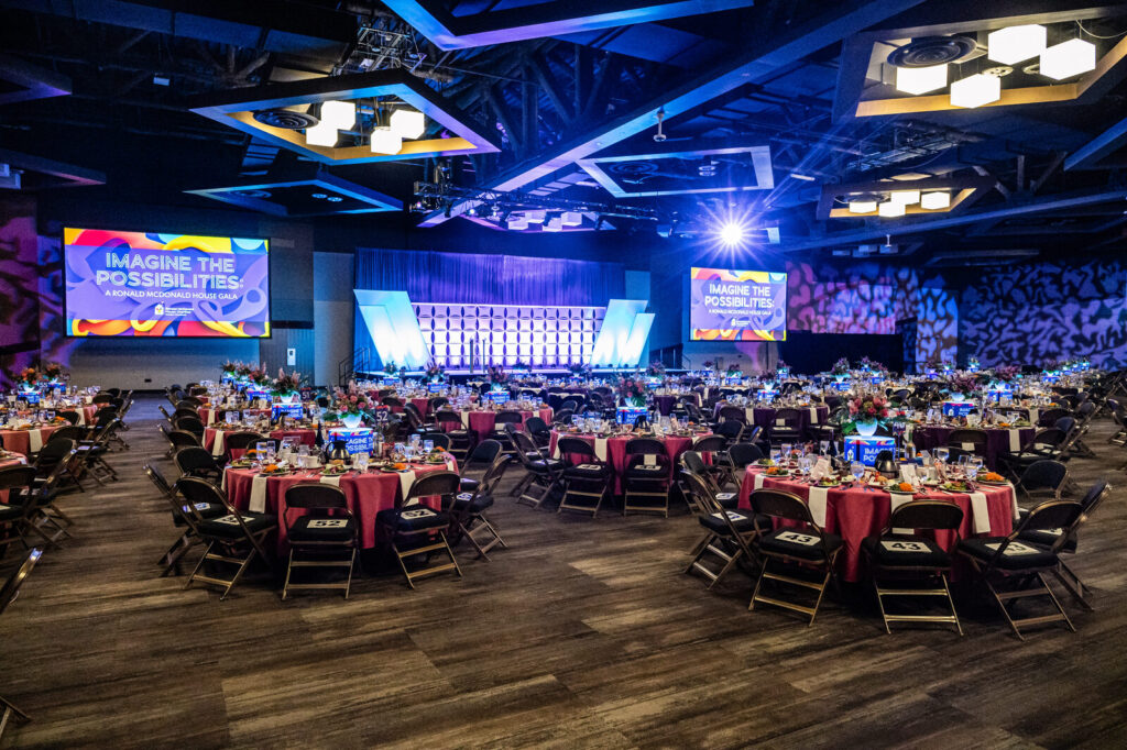 Ballroom set with round tables and stage screens at the Ronald McDonald House Charities gala, Northern Kentucky Convention Center