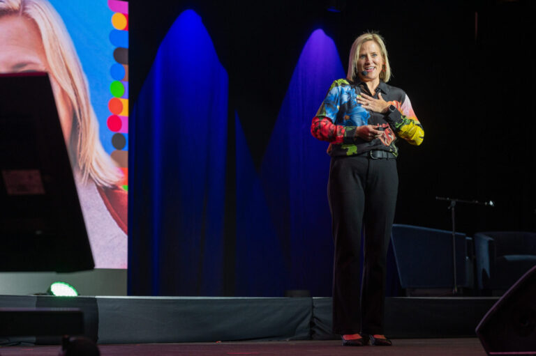 Speaker on stage under colored lights at the Zeno Group P&G GABLE event, Hard Rock Casino Cincinnati