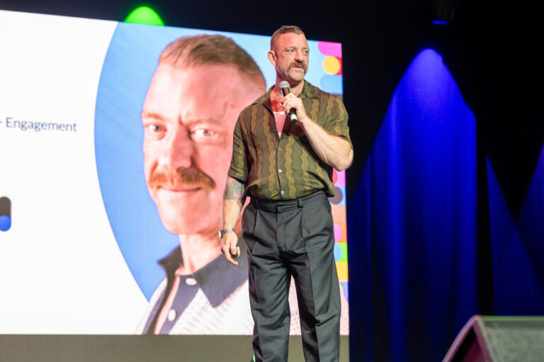 Speaker with a microphone in front of the screen at the Zeno Group P&G GABLE event, Hard Rock Casino Cincinnati