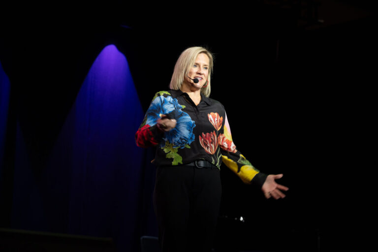 Speaker in a floral blazer on stage at the Zeno Group P&G GABLE event, Hard Rock Casino Cincinnati